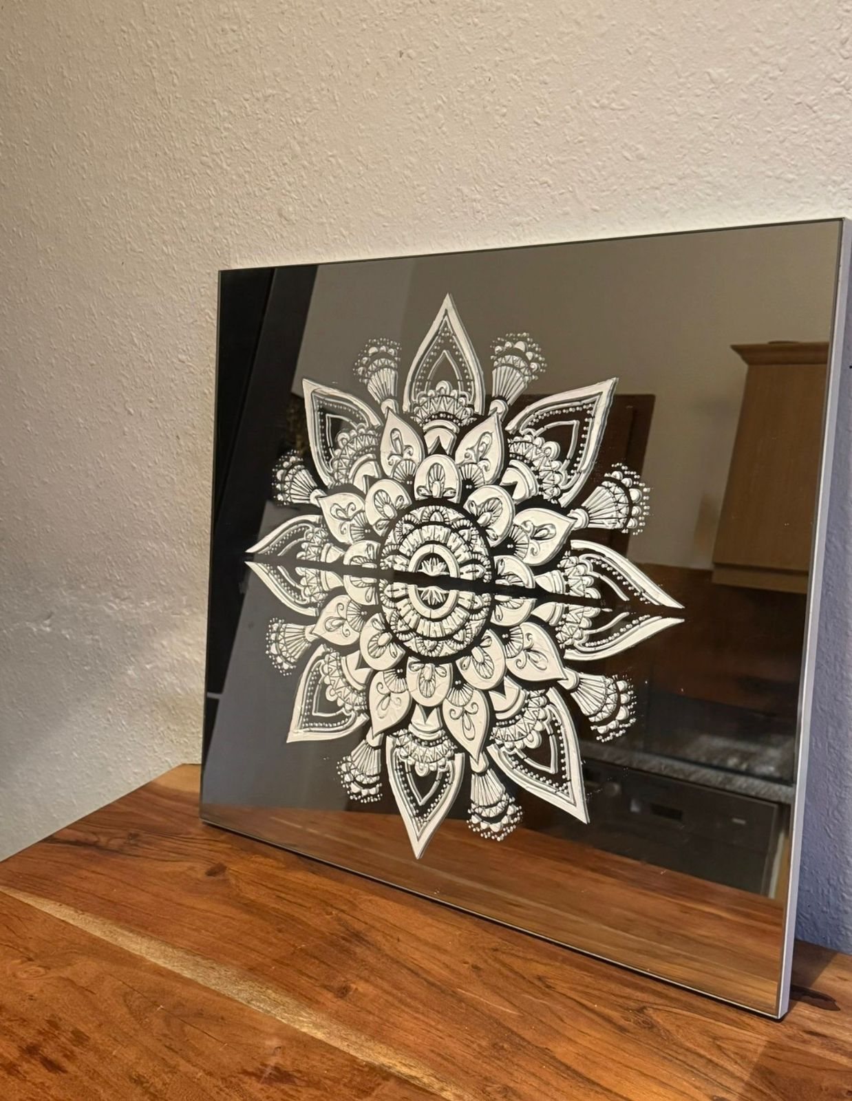 Black and white mandala artwork on a reflective panel