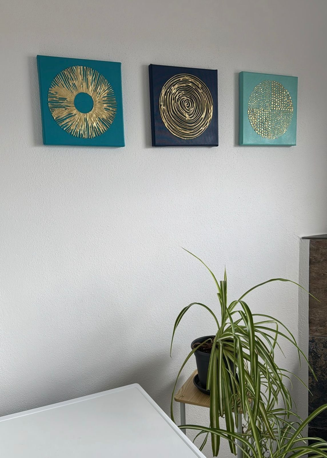 Three turquoise and navy artworks with gold circular details