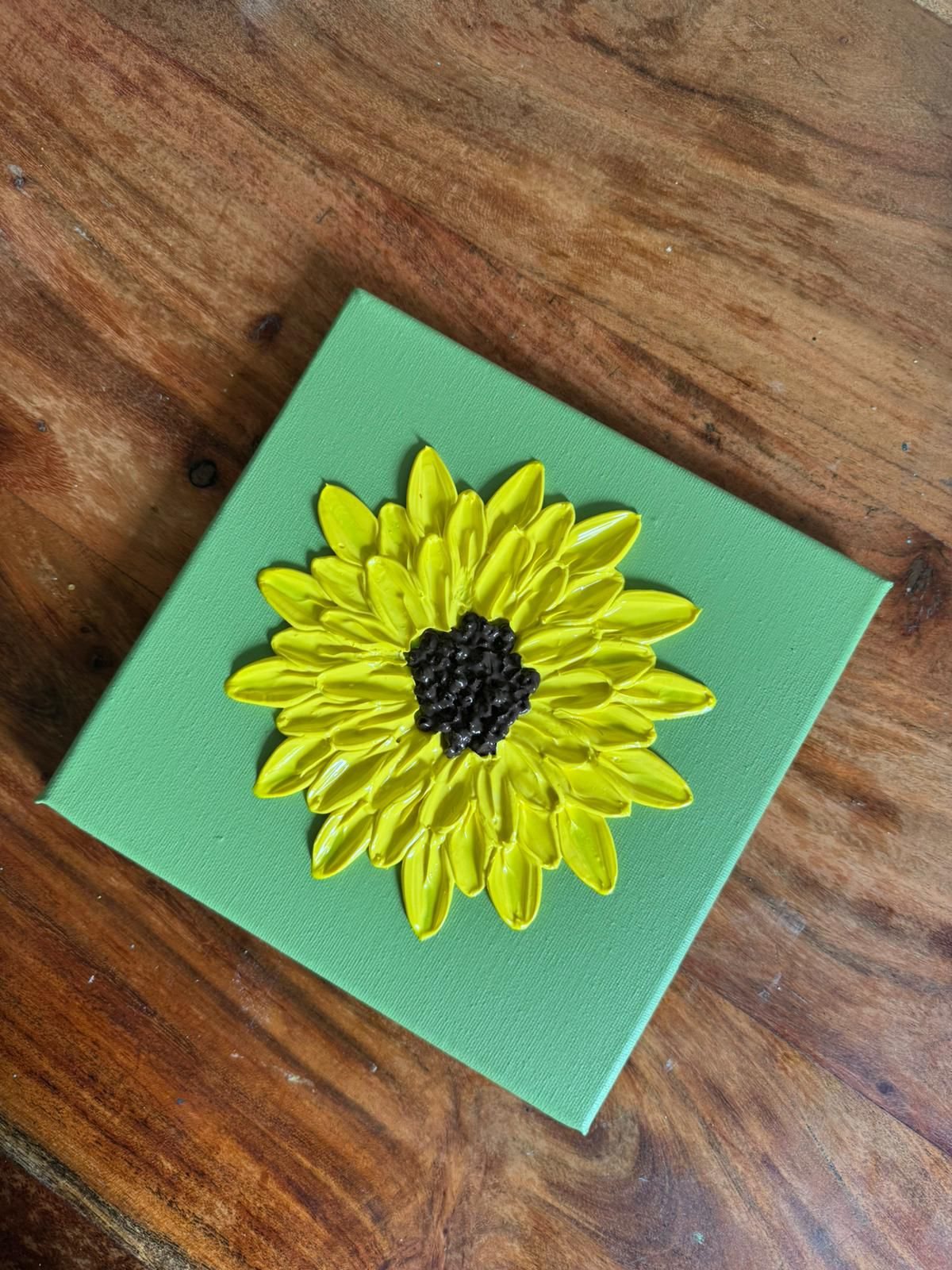 Small yellow sculptural flower artwork on green canvas